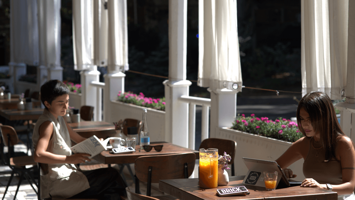 Due ragazze sedute in un ristorante caricano i loro dispositivi con un Brick.