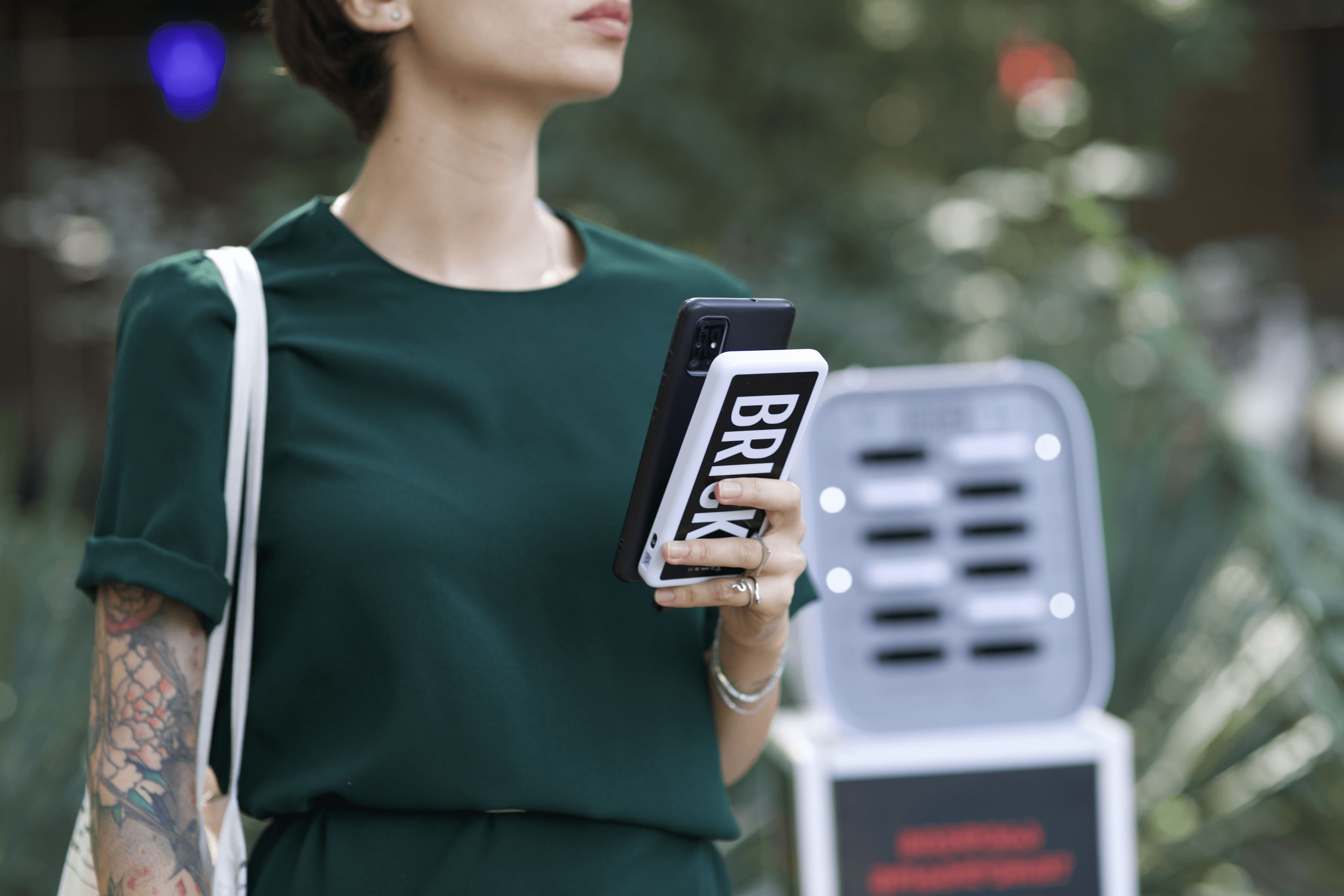 Une femme tenant une banque d'alimentation Brick devant une gare