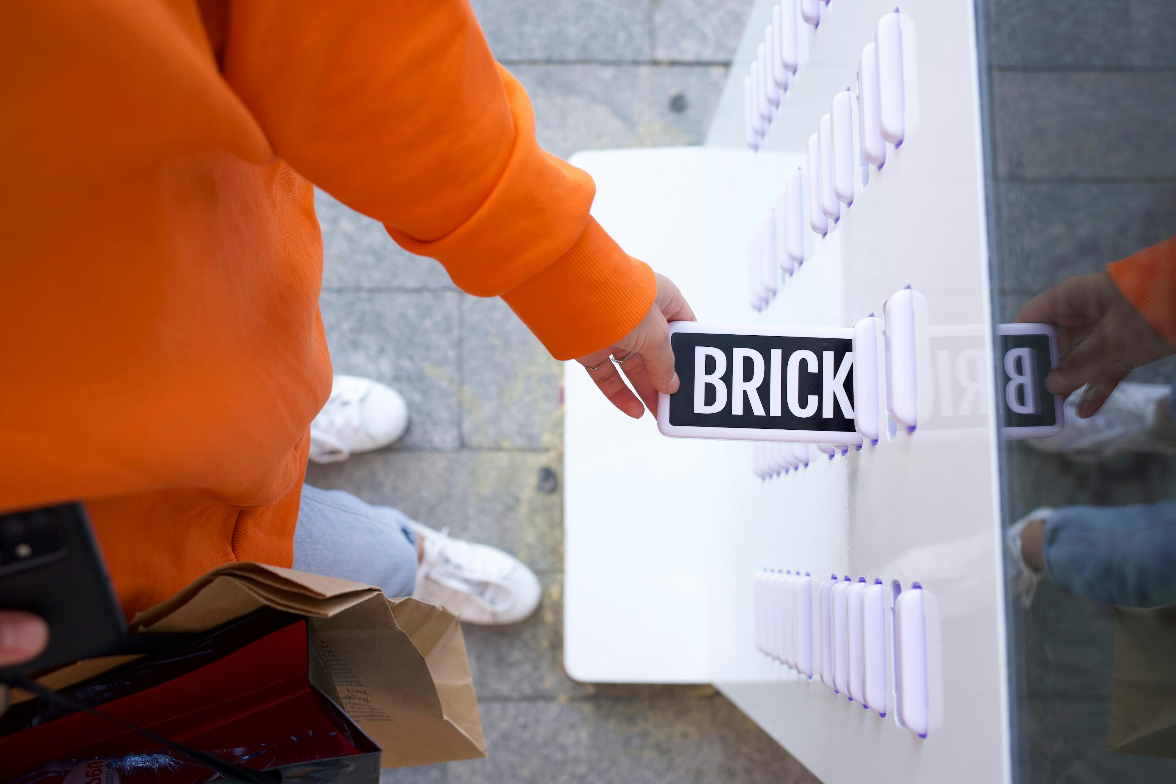 A hand retrieving a Brick power bank from a station